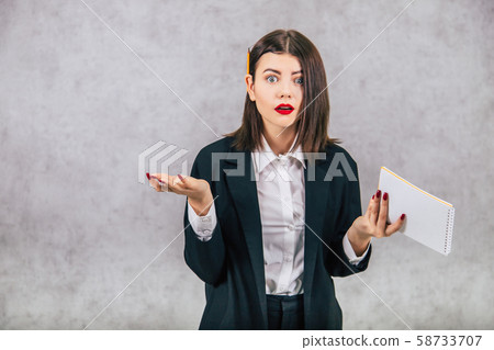 Cute business women standing with pencil behind her ear and asking, puzzled face expression, writing Cute business women standing with pencil behind her ear and asking, puzzled face expression, writing 58733707