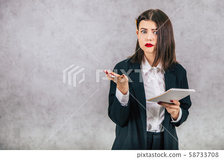 Cute business women standing with pencil behind her ear and asking, puzzled face expression, writing Cute business women standing with pencil behind her ear and asking, puzzled face expression, writing 58733708