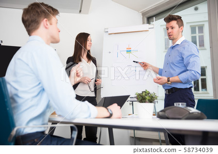 Executive Explaining Presentation To Coworkers In Office Executive Explaining Presentation To Coworkers In Office 58734039