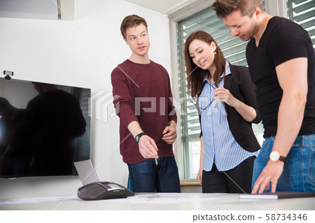 Businessman Explaining Plan To Coworkers At Desk Businessman Explaining Plan To Coworkers At Desk 58734346