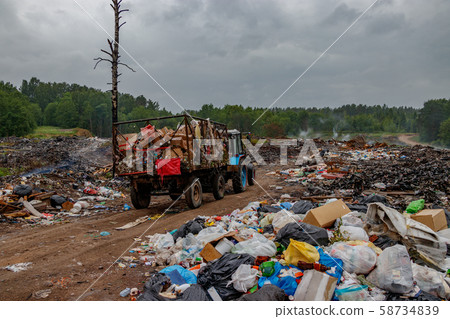The tractor takes the trash to the landfill. Garbage is burned at the dump. Incorrect waste disposal. Sad apocalyptic landscape. The tractor takes the trash to the landfill. Garbage is burned at the dump. Incorrect waste disposal. Sad apocalyptic landscape. 58734839