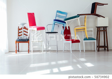 lots of different chairs in the interior of an empty white room 58734902