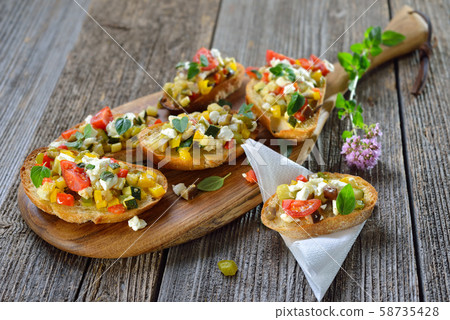 Warm vegetarian canapes: Baked crostini with mixed Greek vegetables with feta cheese 58735428