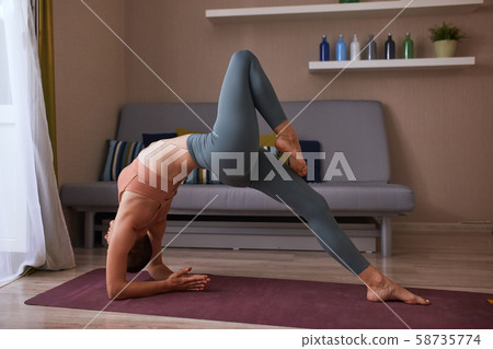 Caucasian short-haired young female doing yoga bridge Caucasian short-haired young female doing yoga bridge 58735774