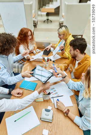 Hardworking designers brainstorming at tables Hardworking designers brainstorming at tables 58739049