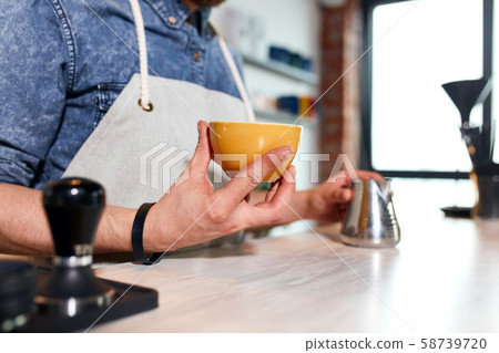 Young barista makes latte in coffee shop Young barista makes latte in coffee shop 58739720