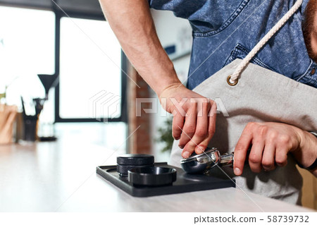 Hands of barista tamping ground coffee 58739732