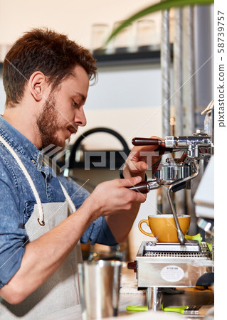 Handsome barman preparing ground coffee for customer in coffee shop. Handsome barman preparing ground coffee for customer in coffee shop. 58739757
