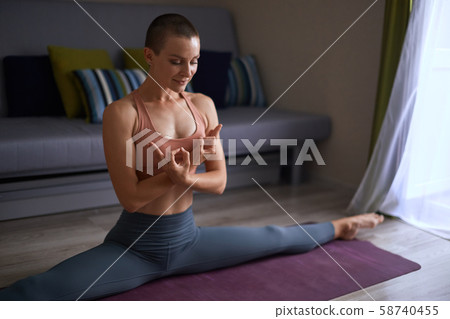Yogi woman at home practicing yoga, doing splits Yogi woman at home practicing yoga, doing splits 58740455