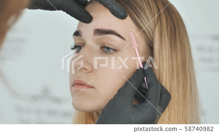 Create permanent eyebrow makeup. Combing eyebrows after dyeing. 58740982