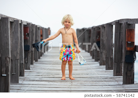Child with mask, fins going to snorkel in tropical 58741142