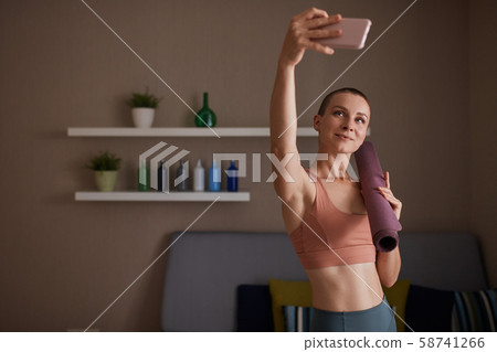 Portrait of attractive young woman folding violet yoga or fitness mat Portrait of attractive young woman folding violet yoga or fitness mat 58741266