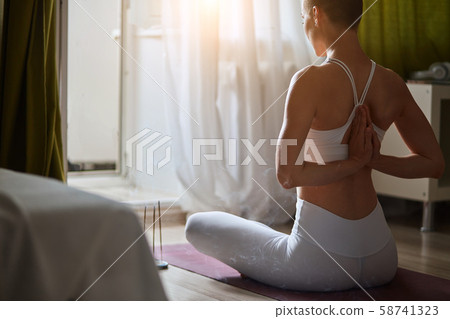 Back view of attractive short-haired girl in sportswear sitting on violet mat Back view of attractive short-haired girl in sportswear sitting on violet mat 58741323
