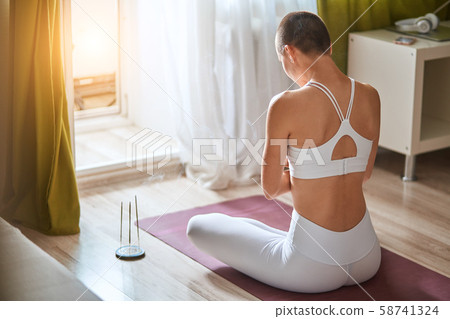 Back view of beautiful short-haired girl in sportswear sitting in lotus position Back view of beautiful short-haired girl in sportswear sitting in lotus position 58741324