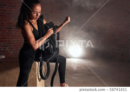 Fitness beautiful woman sitting on fit box with battle rope Fitness beautiful woman sitting on fit box with battle rope 58741831