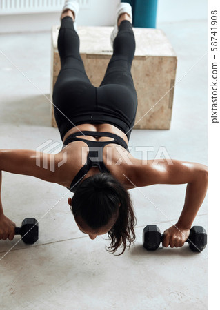 Pretty gym woman push-up dumbbells in gym 58741908