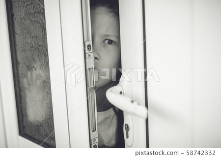 Scared girl kid in opened door. Safety concept 58742332