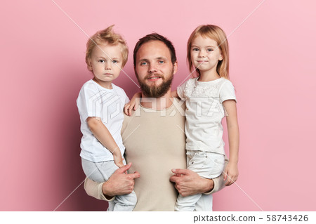 handsome father carrying his little daughter and son on pink background handsome father carrying his little daughter and son on pink background 58743426