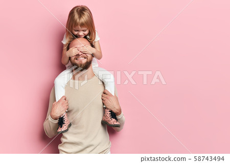 little daughter covering her dad's eyes with a palm 58743494