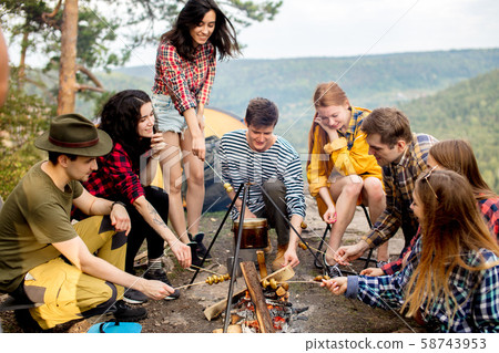 young happy hikers cooking mushrooms on the fire 58743953