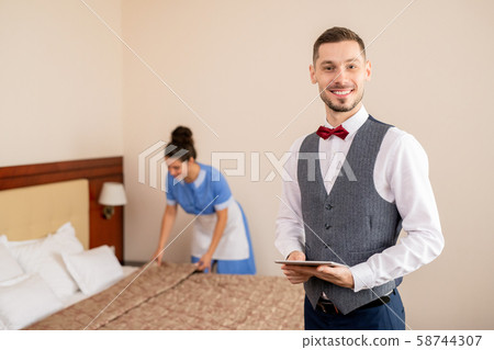 Successful hotel staff standing in front of camera on background of chamber maid 58744307