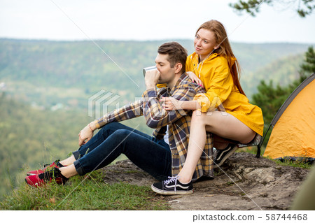 relaxad guy drinking tea while his girlfriend is sitting behind him and hugging 58744468