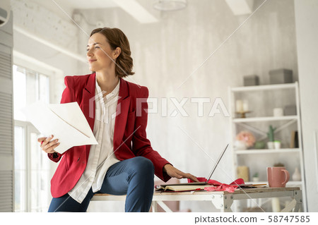 Smiling young woman designer with her sketches Smiling young woman designer with her sketches 58747585