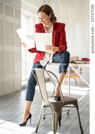 Happy fashion designer looking at her sketches Happy fashion designer looking at her sketches 58747586