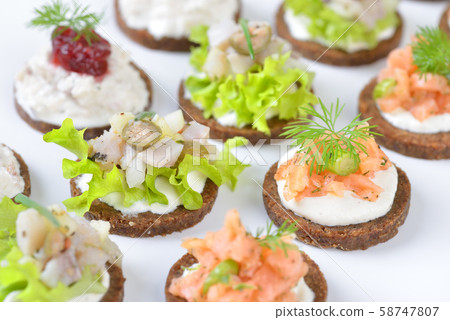 Fish finger food  with salmon tartar, trout mousse with caviar and herring salad on pumpernickel 58747807