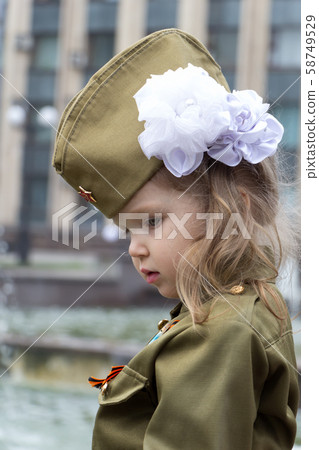 Little girl dressed in military uniform on background of fountains near the government building 58749529