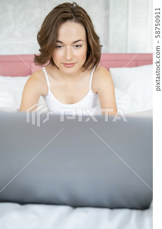 Smiling female sitting in front of her laptop Smiling female sitting in front of her laptop 58750911