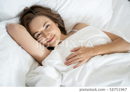 Pleased good-looking female lying in her bed 58751967