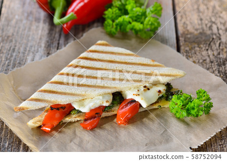 Vegetarian toast:  Panini with grilled red bell peppers and feta cheese on pesto sauce 58752094