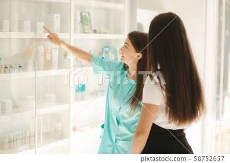 Female cosmetologis show to client cosmetology product. Doctor recommends different serum and face 58752657