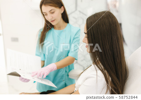 Female cosmetologist speak with woman and show result of previous work. Cosmetology clinic Female cosmetologist speak with woman and show result of previous work. Cosmetology clinic 58752844