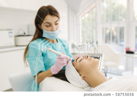 Professional female cosmetologist doing hydrafacial procedure in Cosmetology clinic. Doctor use 58753038