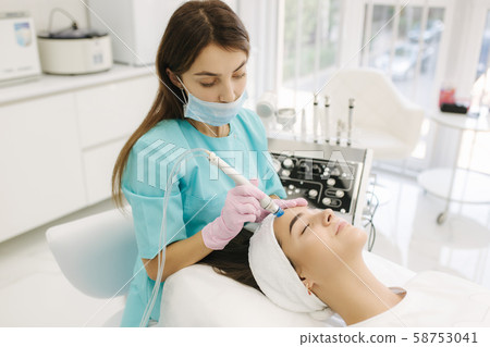 Professional female cosmetologist doing hydrafacial procedure in Cosmetology clinic. Doctor use 58753041