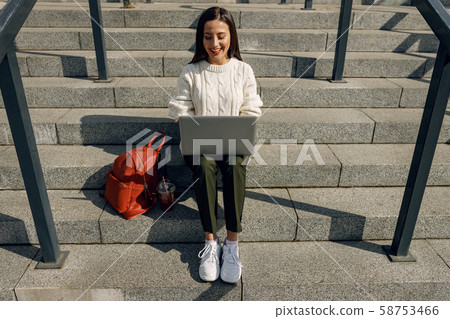 Cheerful freelancer working outdoors in the city center 58753466