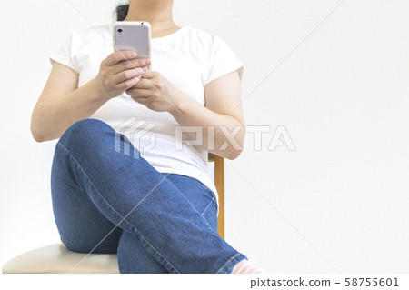 一個小胖女人坐在椅子上,操作智能手機 一個小胖女人坐在椅子上,操作智能手機 58755601