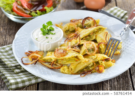 Fried Swabian ravioli ('Maultaschen') with vegetarian filling served with roasted onions  58761454