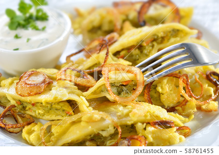 Fried Swabian ravioli ('Maultaschen') with vegetarian filling served with roasted onions Fried Swabian ravioli ('Maultaschen') with vegetarian filling served with roasted onions 58761455