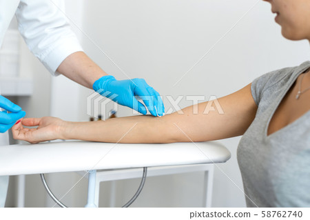 A nurse wipes a patients hand with a cotton pad 58762740
