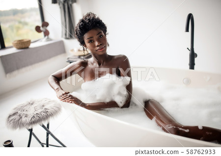 Beautiful dark-eyed woman lying in bath with foam Beautiful dark-eyed woman lying in bath with foam 58762933