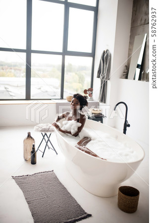 Naked dark-skinned woman feeling good having foamy bath Naked dark-skinned woman feeling good having foamy bath 58762937