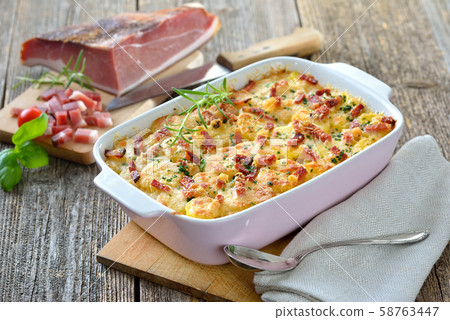 Hearty potato gratin with parmesan cheese, cream and delicious cured bacon from South Tyrol Hearty potato gratin with parmesan cheese, cream and delicious cured bacon from South Tyrol 58763447
