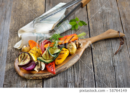 Vegan cuisine: Mixed grilled vegetables on a wooden cutting board Vegan cuisine: Mixed grilled vegetables on a wooden cutting board 58764149
