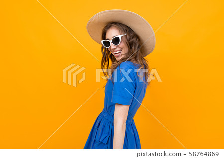 photo from behind a girl in a blue dress on a yellow background, stylish woman in a hat and glasses photo from behind a girl in a blue dress on a yellow background, stylish woman in a hat and glasses 58764869