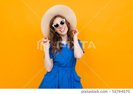 stylish girl tourist on an orange background looking at the camera with a smile stylish girl tourist on an orange background looking at the camera with a smile 58764870