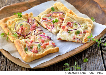 Tarte Flambee from Alsace with onions and bacon, similar to a pizza, thin dough with sour cream 58764967