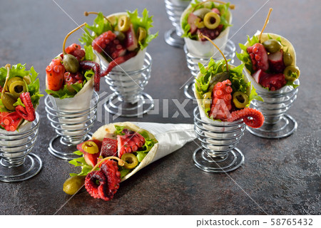 Mini tortillas stuffed with octopus salad with olives and capers, served in wire egg cups 58765432